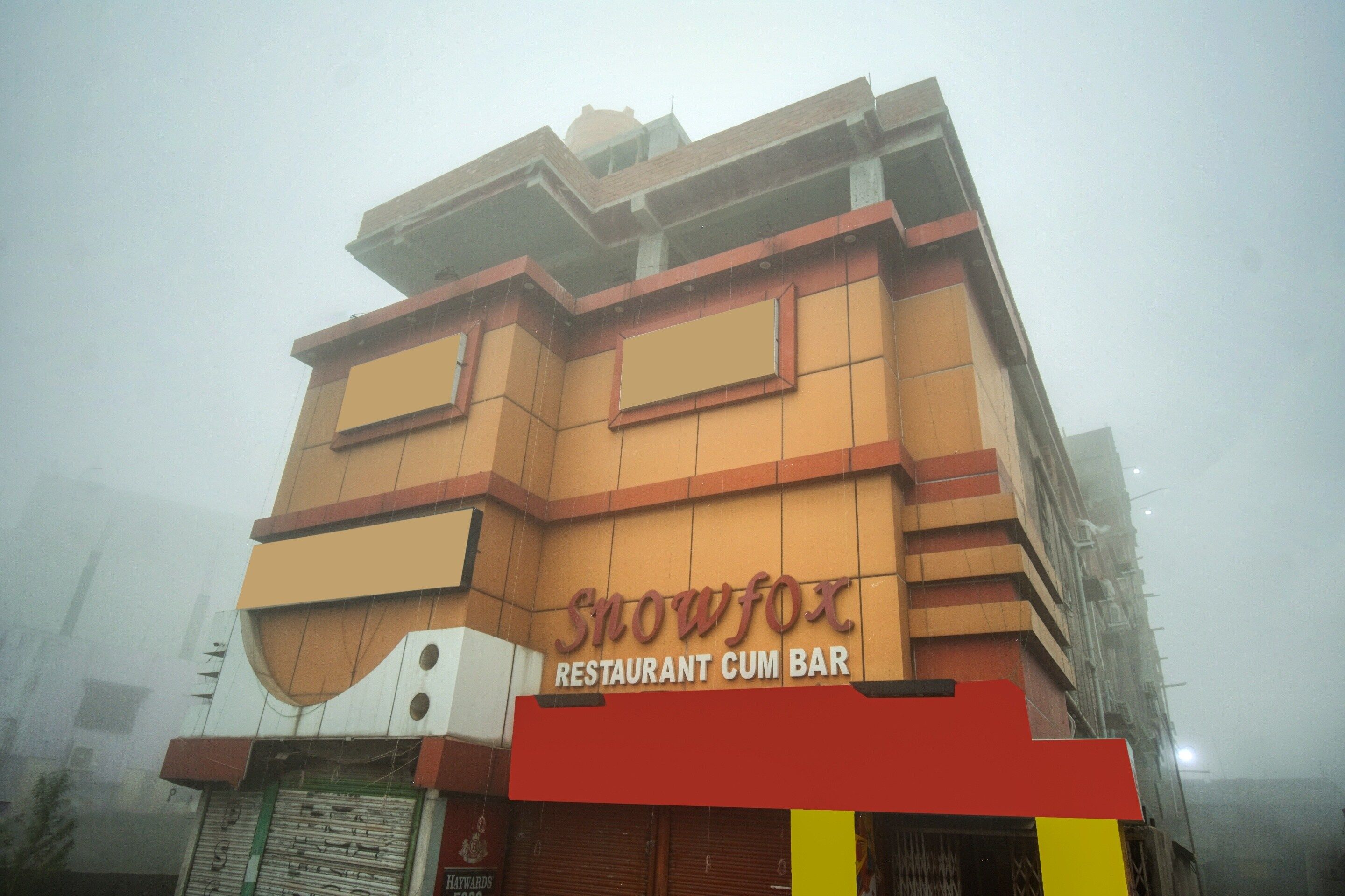 A multi-story building with a prominent signage for 'Snowfox Restaurant Cum Bar' on the ground floor.