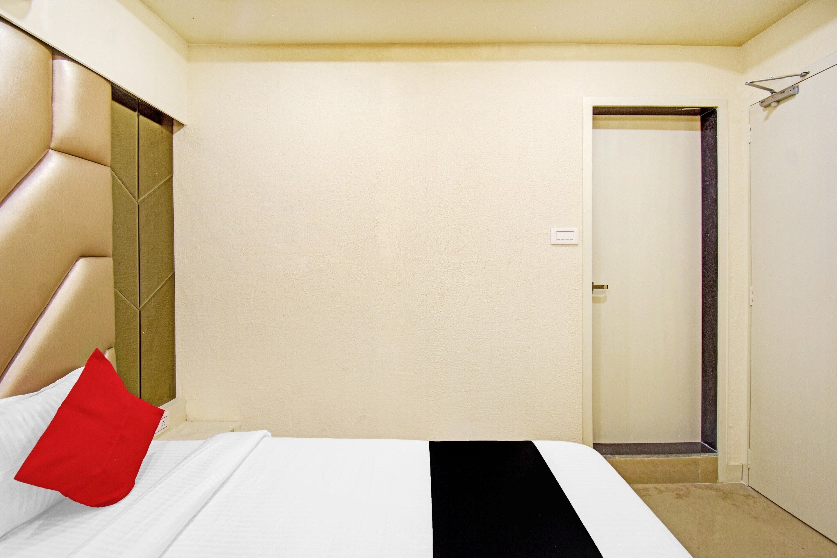 Una habitación de hotel con una cama, una puerta y una pared.
