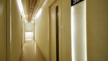 A hotel corridor with a number sign indicating room 301, a door with a giraffe pattern, and a light switch on the wall.
