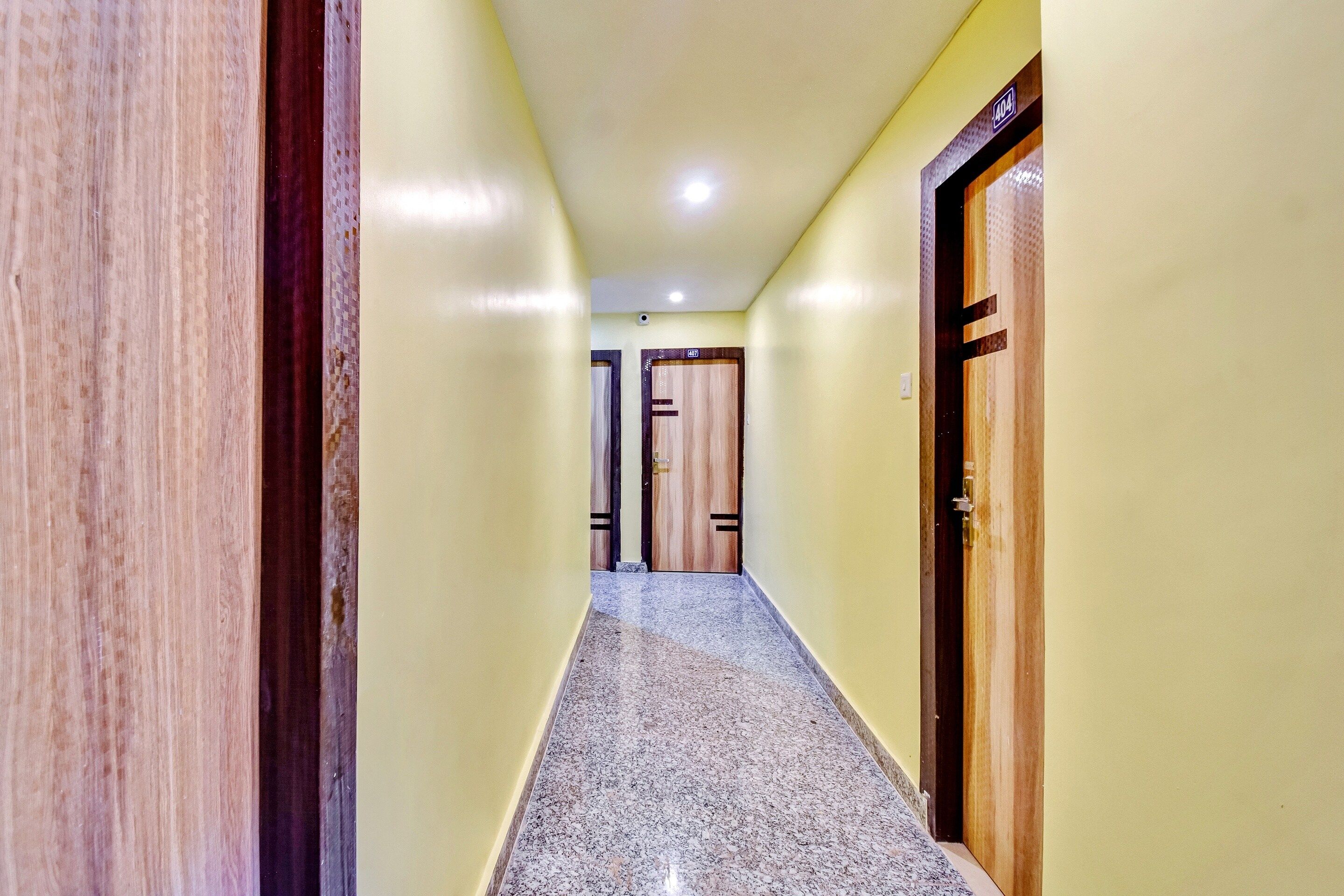 A hallway with a marble floor, wooden doors, and a ceiling light.