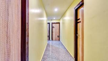 A hallway with a marble floor, wooden doors, and a ceiling light.