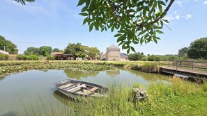 A tranquil pond with a small boat, surrounded by lush greenery and a traditional building in the background. - New Listing (Thouars)