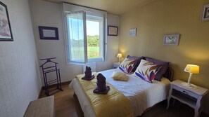 Ein Hotelzimmer mit Bett, Nachttisch, Fenster und Wanddekorationen.