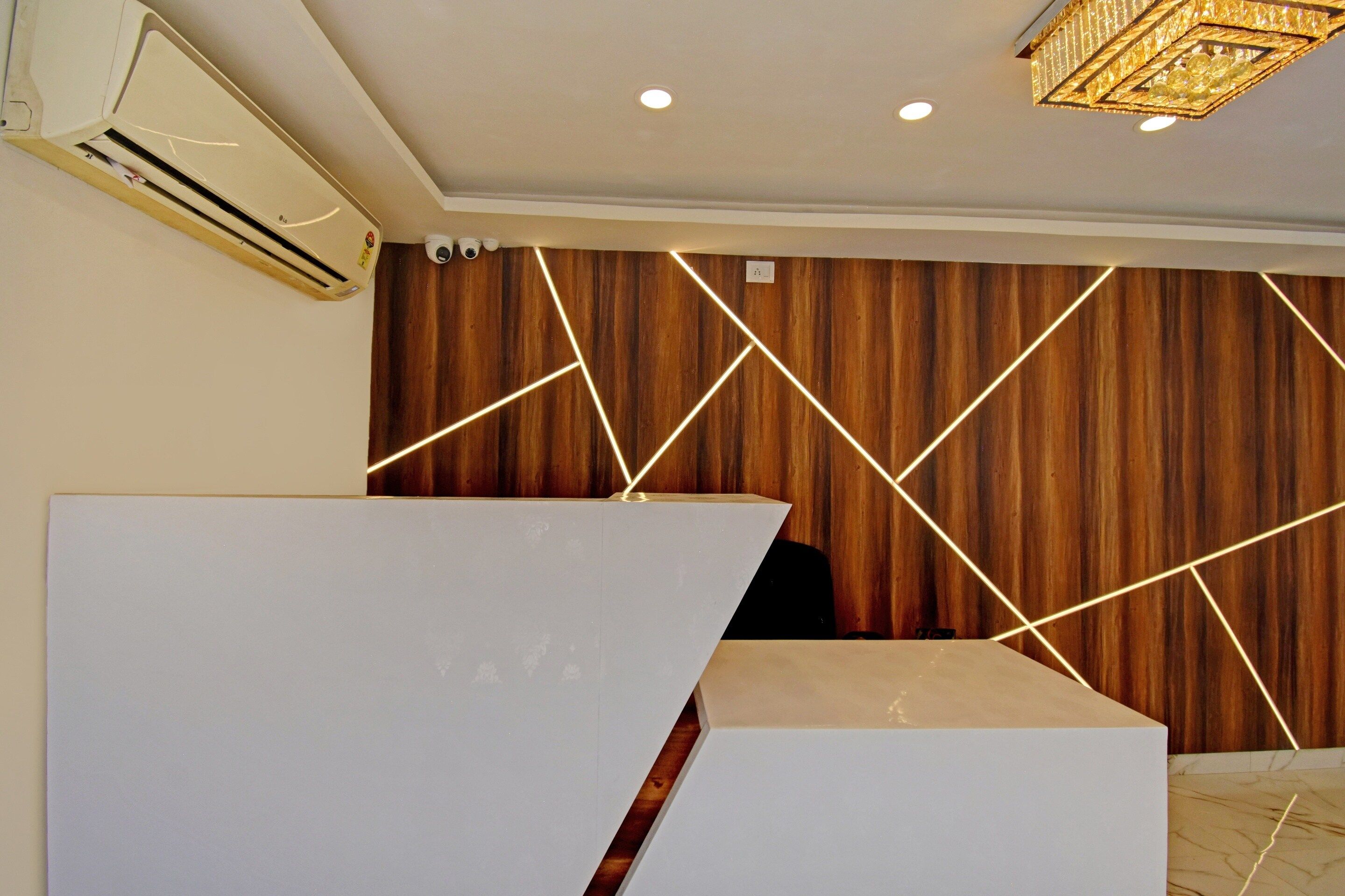 Ein Empfangsbereich modernen Designs mit einer Wand aus Holzpaneelen und geometrischen Lichtmustern.