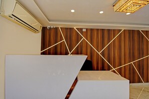 Zona de recepción con diseño moderno, que incluye un panel de pared de madera y patrones de luz geométricos.