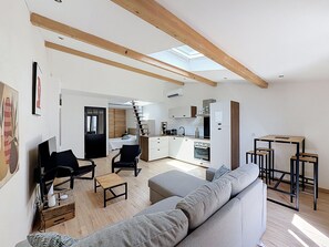 A modern apartment with a loft-style living area, a kitchen with a built-in oven, and a dining area with a high table. - New Listing (Mèze)