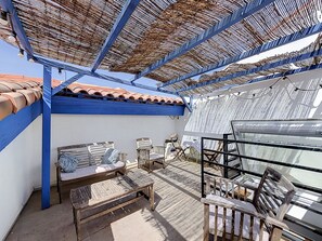 A covered outdoor seating area with a thatched roof, a white wall, and a tiled roof section. - New Listing (Mèze)