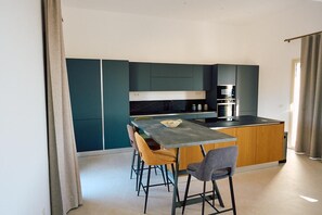 A modern kitchen with a central island, bar stools, and a dining table. - New Listing (Sicilia)