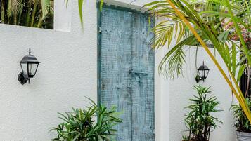 A white wall with a blue door, two potted plants, and two wall-mounted lights.