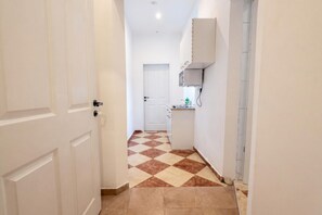 A narrow hallway with a checkered floor, white walls, and a door leading to a room. - A Little Vienna for Two near Westbahnhof (Vienna)
