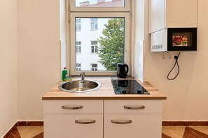 Eine Küchenzeile mit Fenster, Spüle, Herd und Mikrowelle.