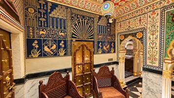 Une pièce ornée de carreaux décoratifs, dotée d’une grande porte en bois et de deux chaises en bois.