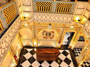 Rebost d'hotel amb decoració ornamentada, sòl de pissos i una zona d'estar central.
