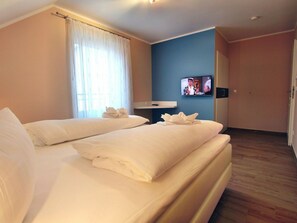 Una habitación de hotel con dos camas, un televisor en la pared y un baño.
