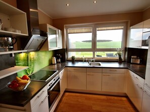 Una cocina moderna con un ventanal amplio, una estufa empotrada y un frutero sobre la encimera.