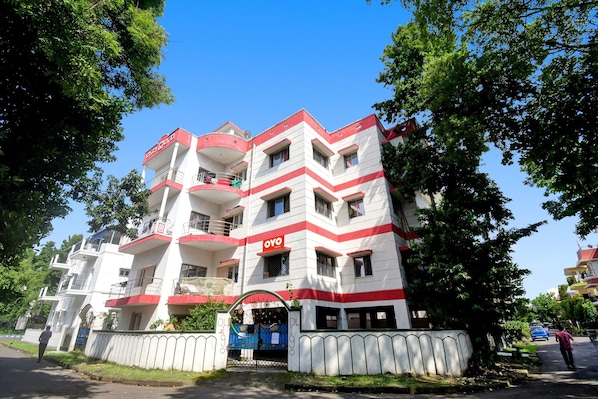 A multi-story building with balconies, a gated entrance, and a sign indicating it is a hotel.