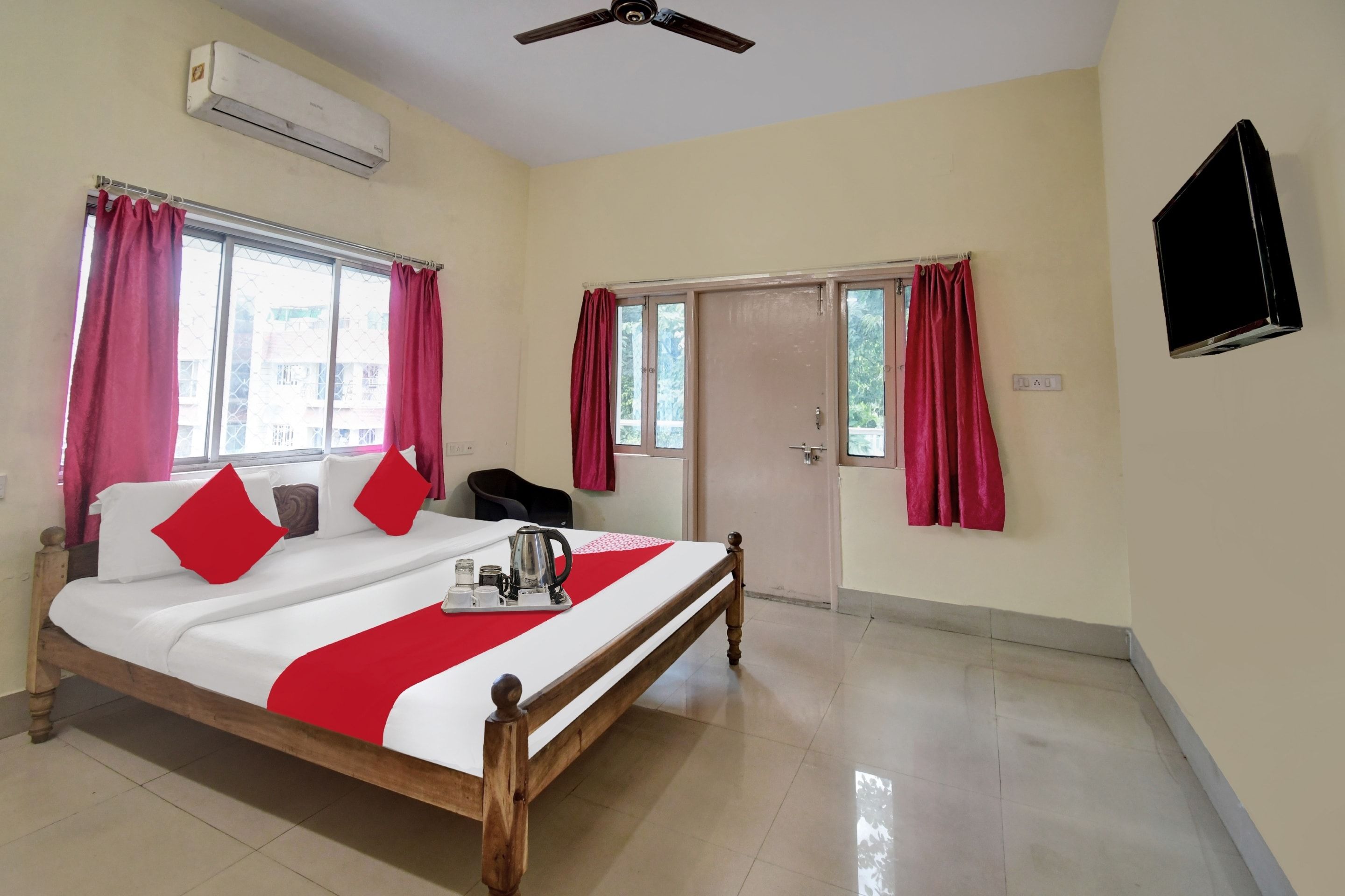 Una habitación de hotel con cama, cafetera y televisión en la pared.