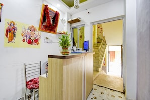 A reception area with a desk, chair, and a potted plant. - Hotel O Ankita Guest House (Kolkata)