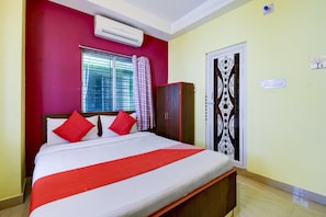 A bedroom with a bed, a wardrobe, a window with curtains, and an air conditioning unit. - Hotel O Ankita Guest House (Kolkata)