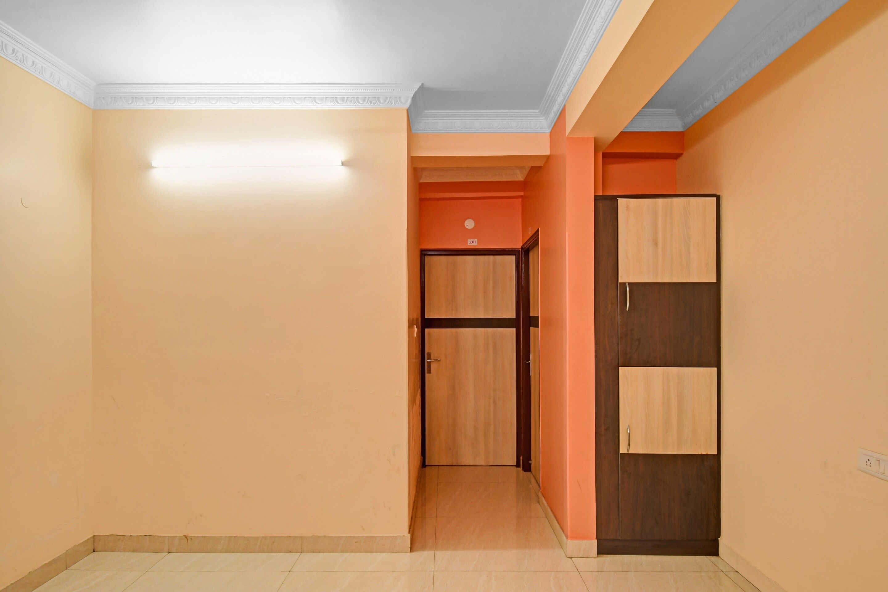 A hallway with a door leading to a room, a light switch, and a wall-mounted electrical outlet.