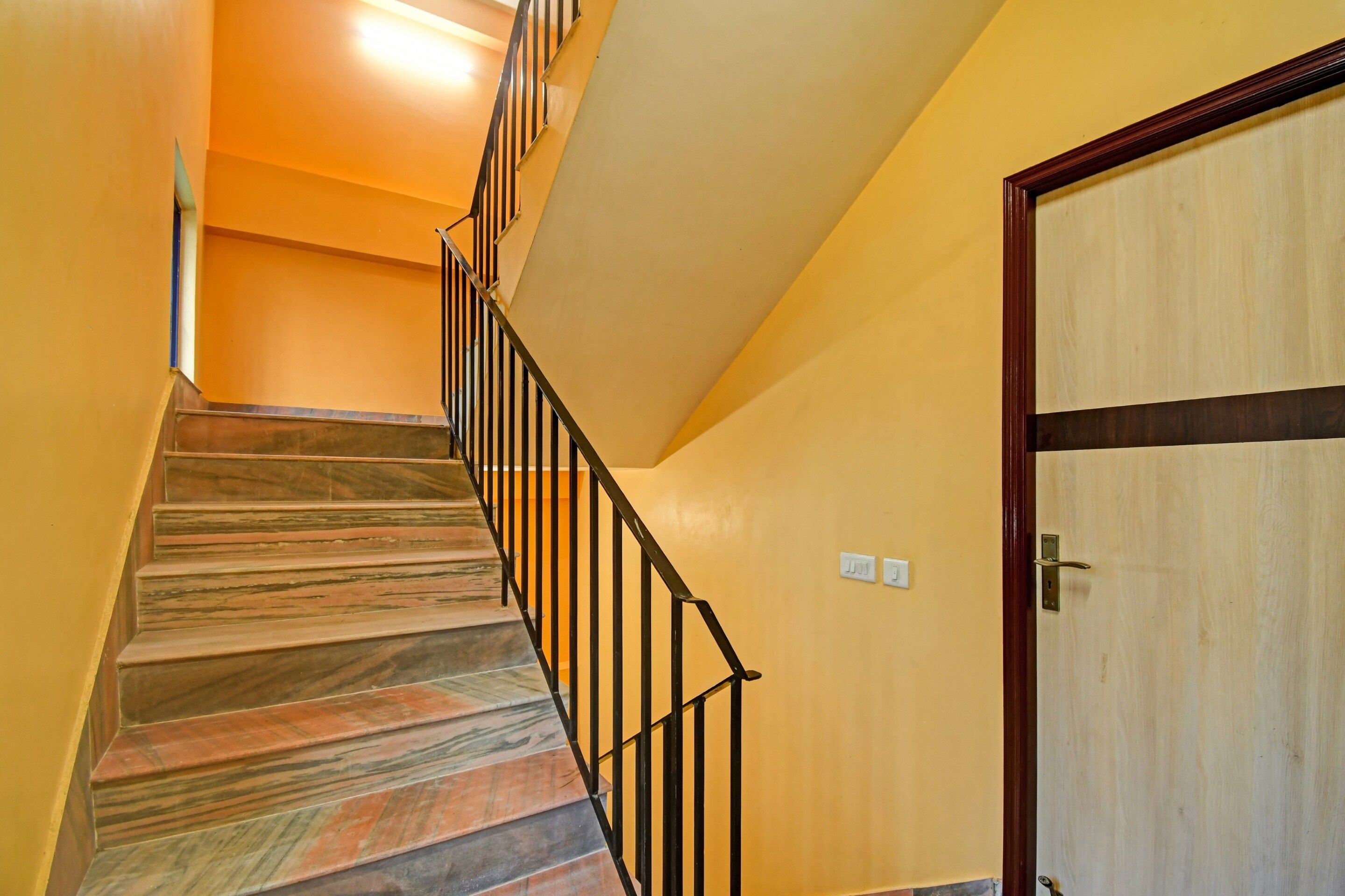 A staircase with a wooden finish and black railings leading to a door with a wooden frame.
