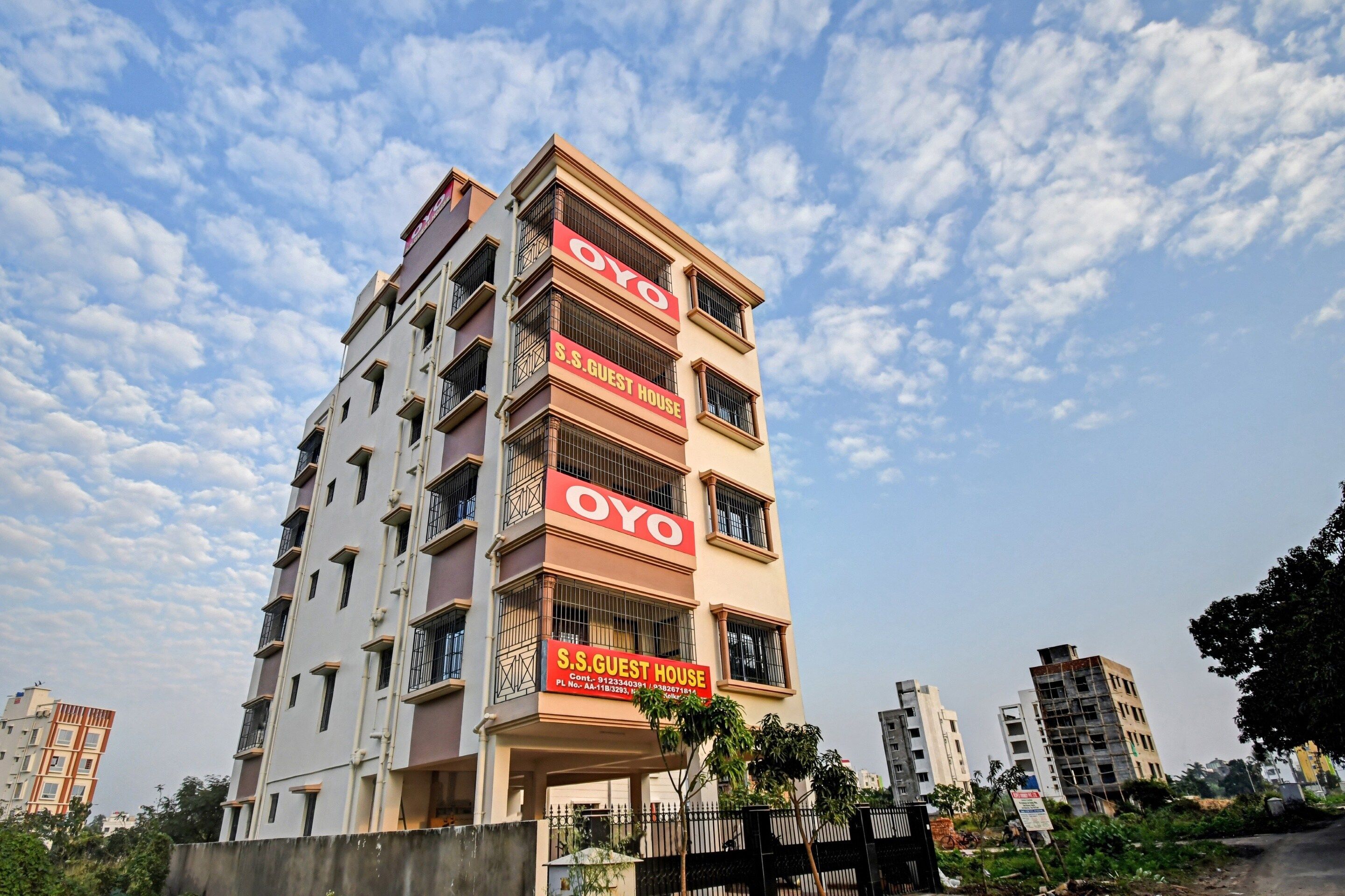 A multi-story building with balconies and a sign indicating it is a guest house.