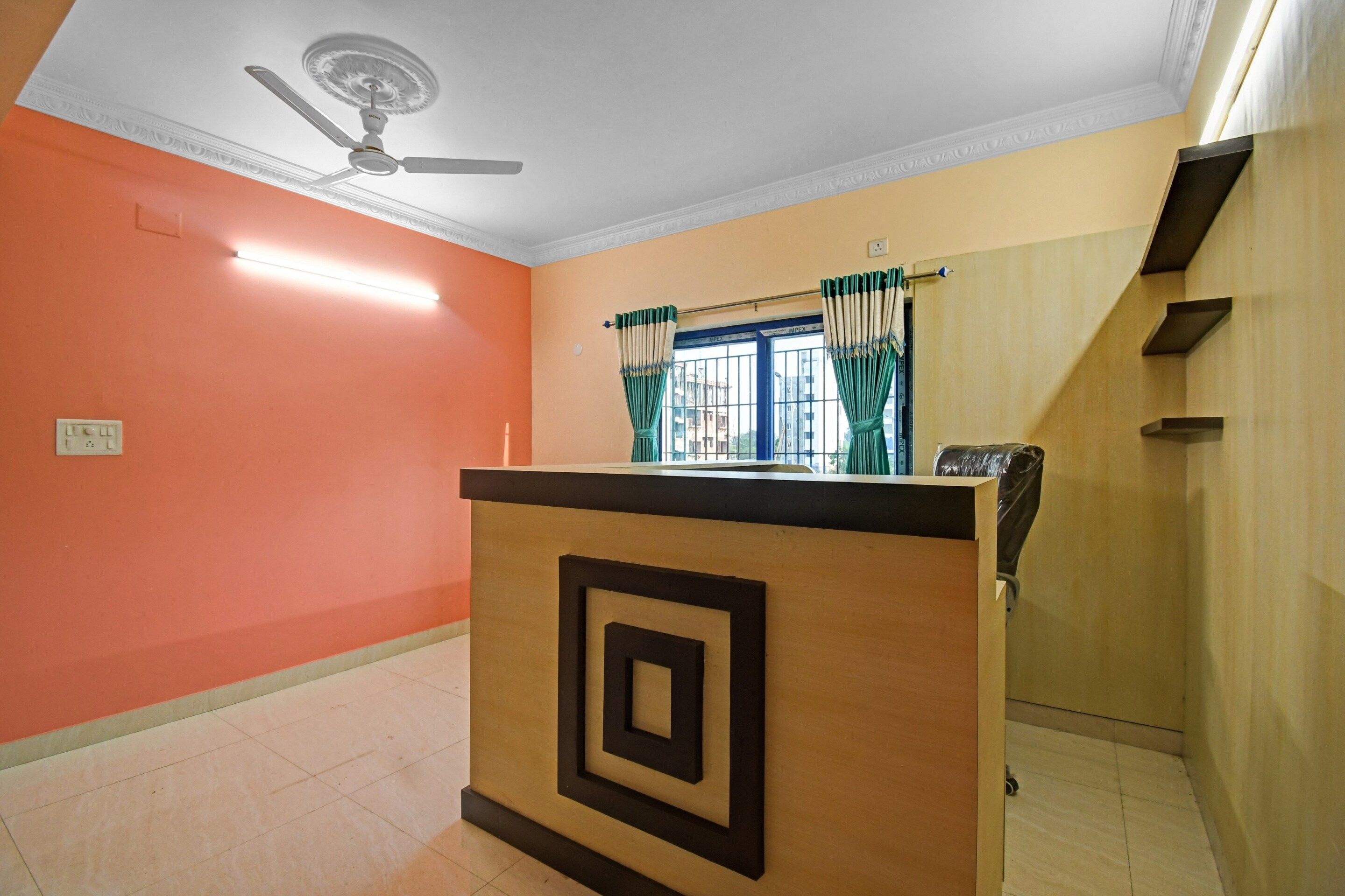 A room with a ceiling fan, a window with curtains, a wooden counter, and a tiled floor.