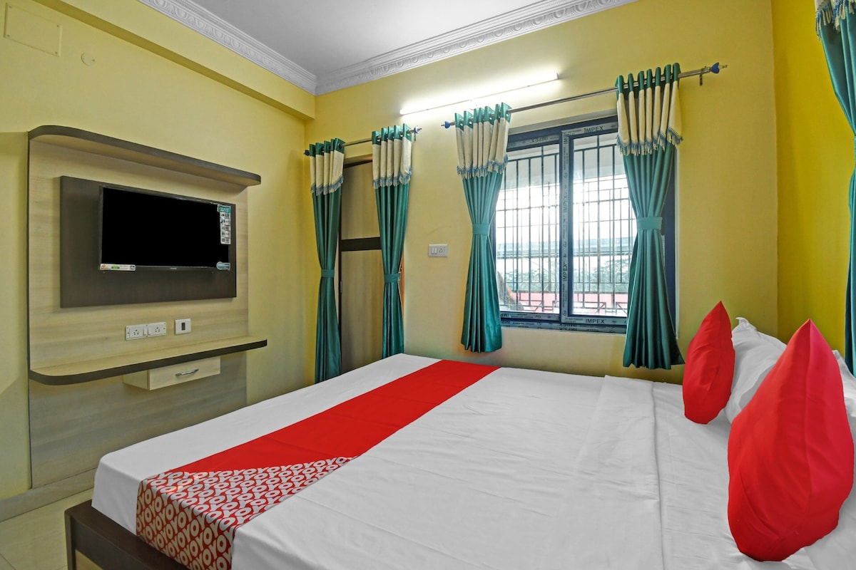 Quarto de hotel com cama, televisão, cortinas e janela.