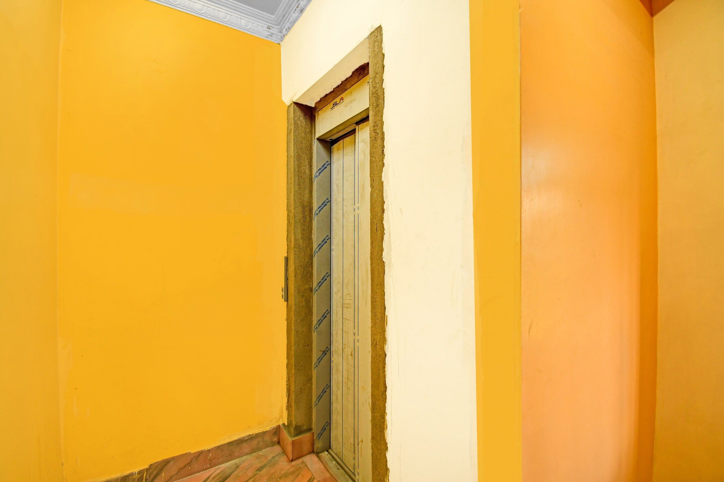 A narrow hallway with yellow walls and a door with a white frame.