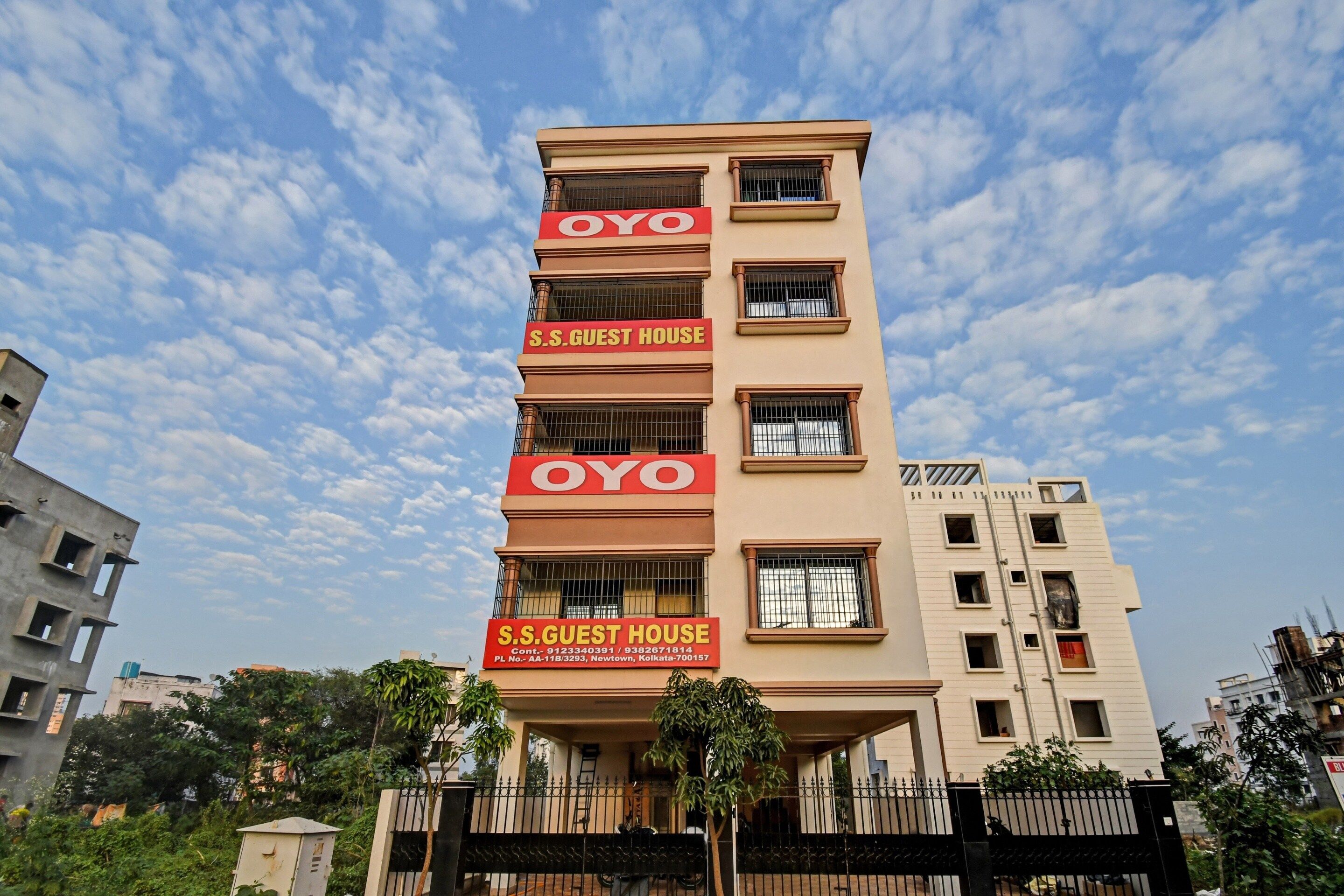 A multi-story building with a prominent red sign indicating it is a guest house.