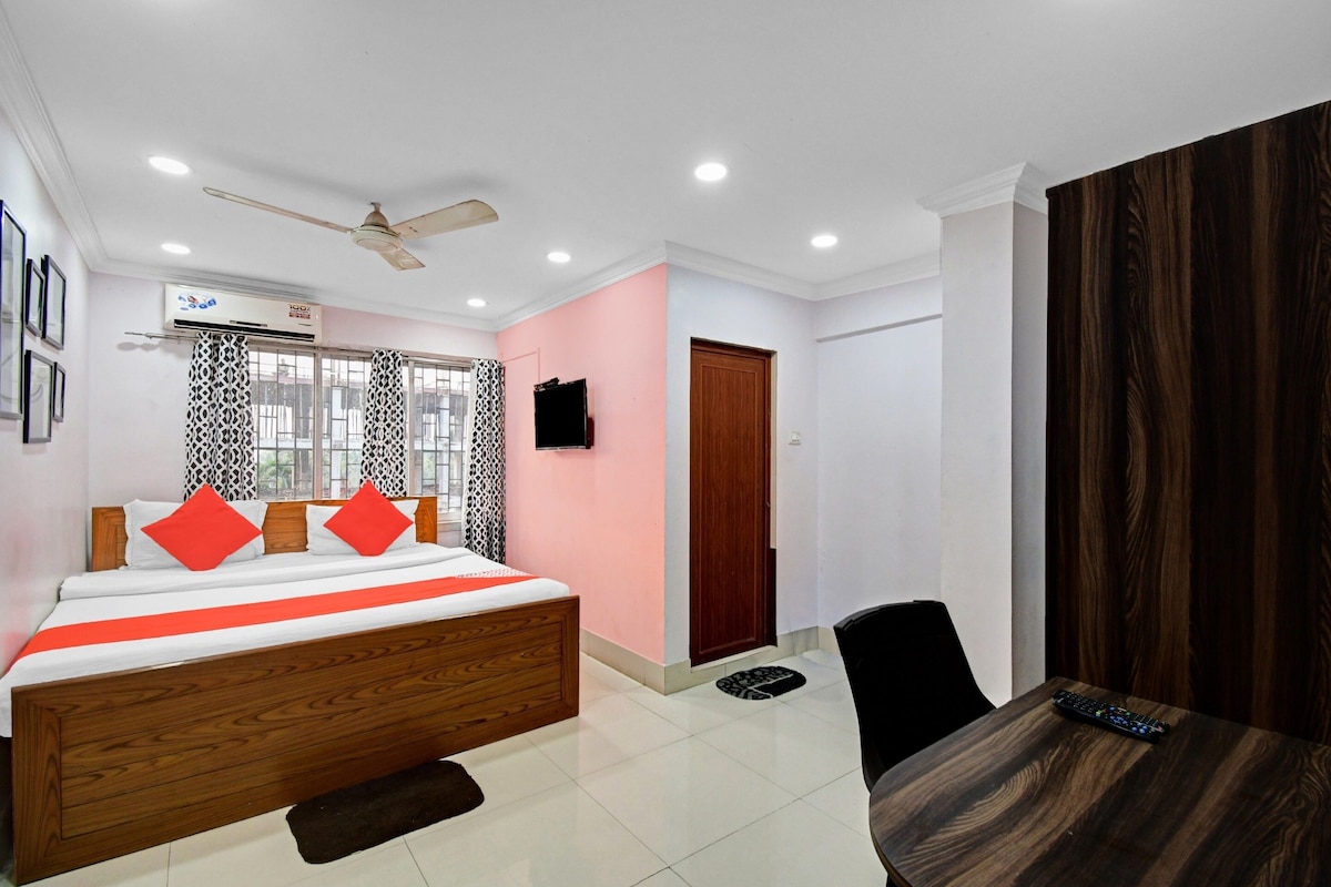A bedroom with a bed, a ceiling fan, an air conditioning unit, a TV, and a wooden wardrobe.
