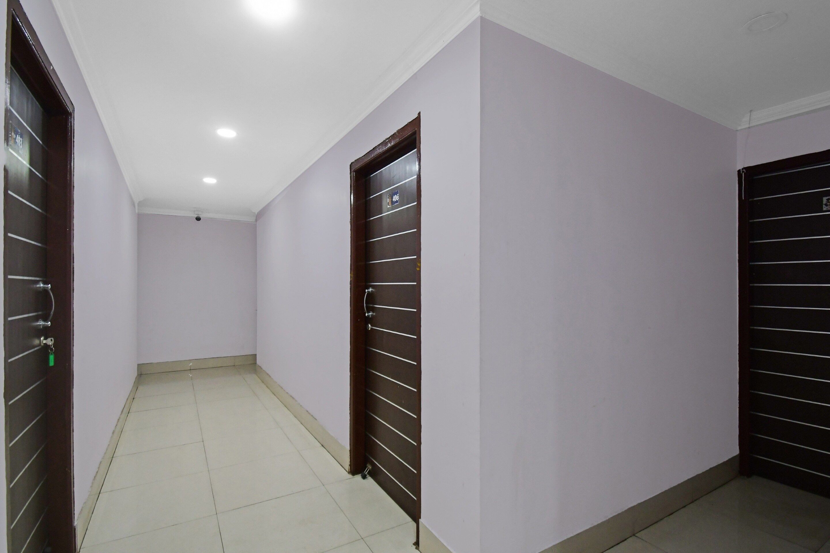 A corridor with two doors, each with a metal grid design, and a tiled floor.