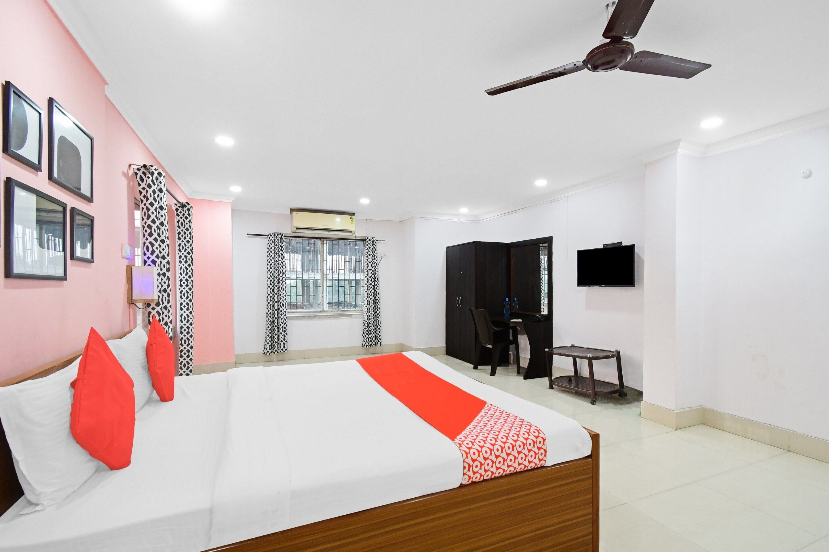 A hotel room with a bed, a desk, a chair, a TV, and a ceiling fan.