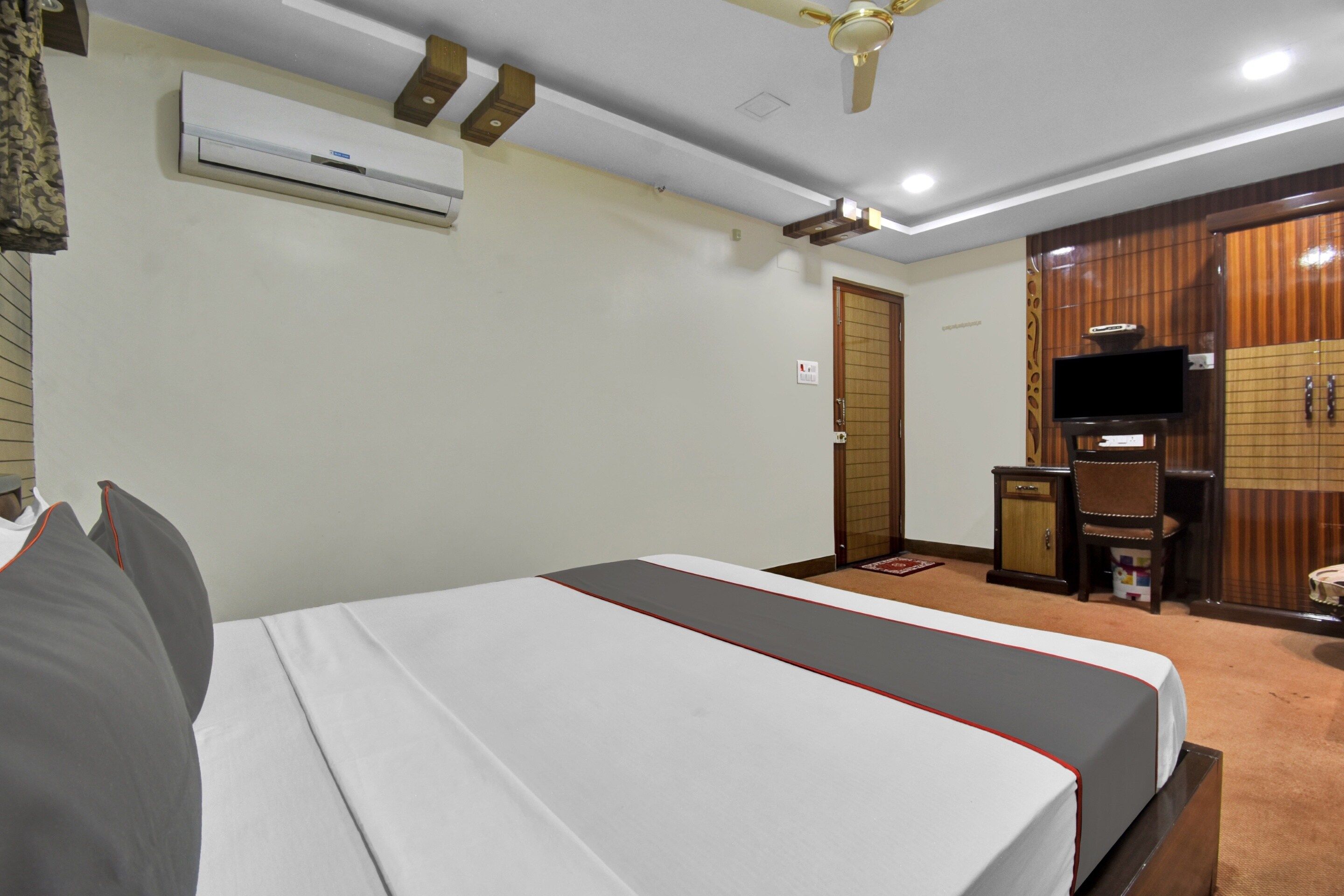 Una habitación de hotel con cama, aire acondicionado, televisor y armario.