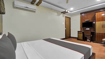Una habitación de hotel con cama, aire acondicionado, televisor y armario.