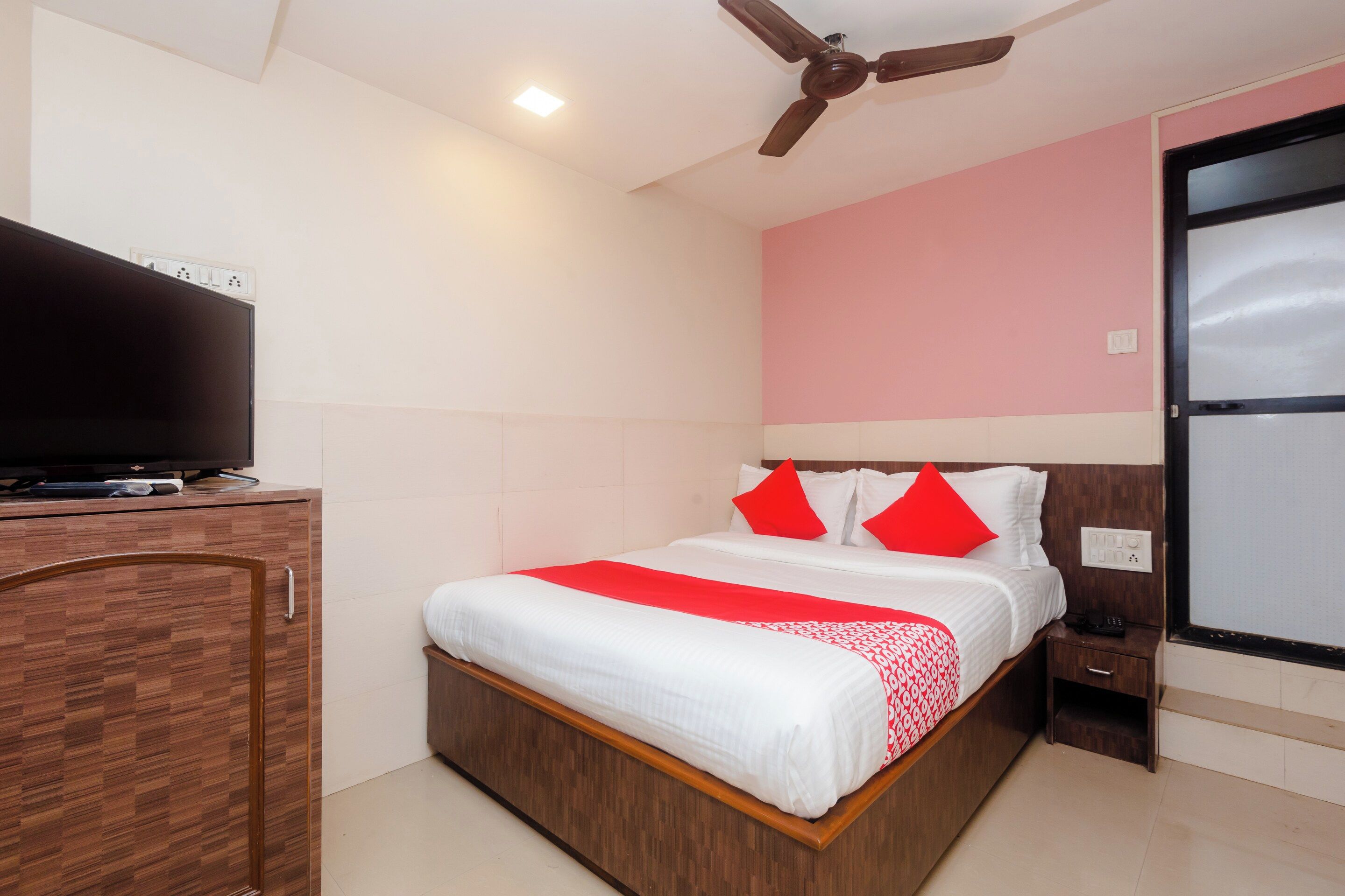 A hotel room with a bed, a television, a ceiling fan, and a nightstand.