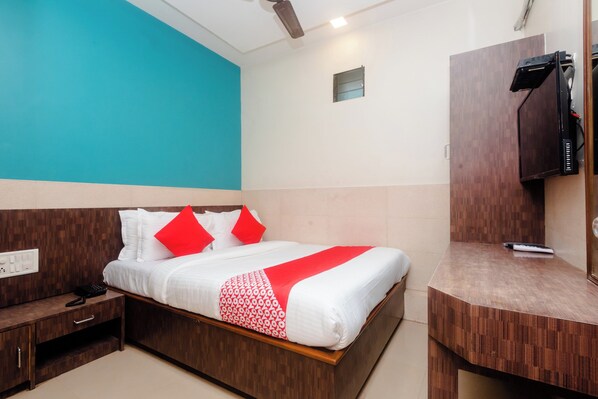 A hotel room with a bed, a desk, a TV, and a small window. - Hotel O Royal Residency (Mumbai)