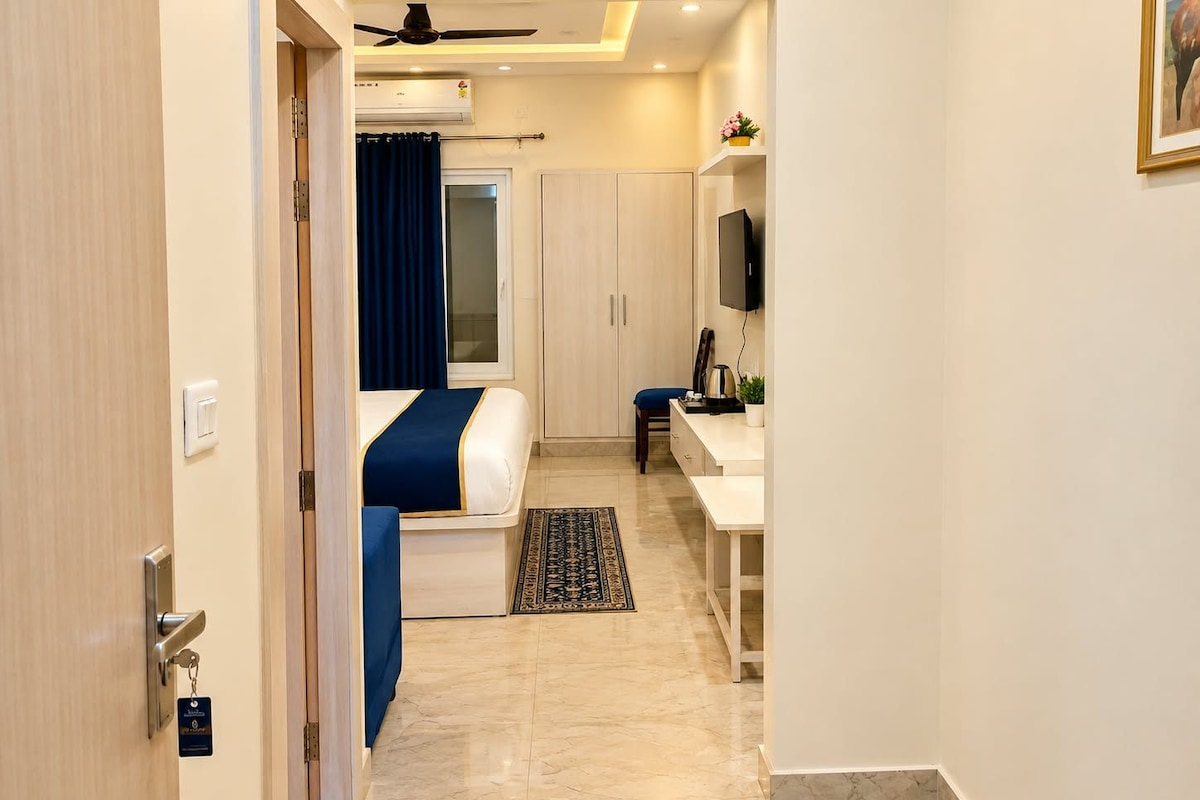 Una camera d'albergo con un letto, una scrivania, una sedia, una televisione e un bagno con doccia e WC.