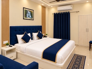 Una camera d'albergo con un letto grande, un comodino, una tenda e un armadio. È presente anche un condizionatore d'aria fissato al muro.