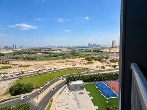 Ein Hochhaus mit Blick auf eine Stadtlandschaft, darunter Straßen, Fahrzeuge und ein Sportplatz.