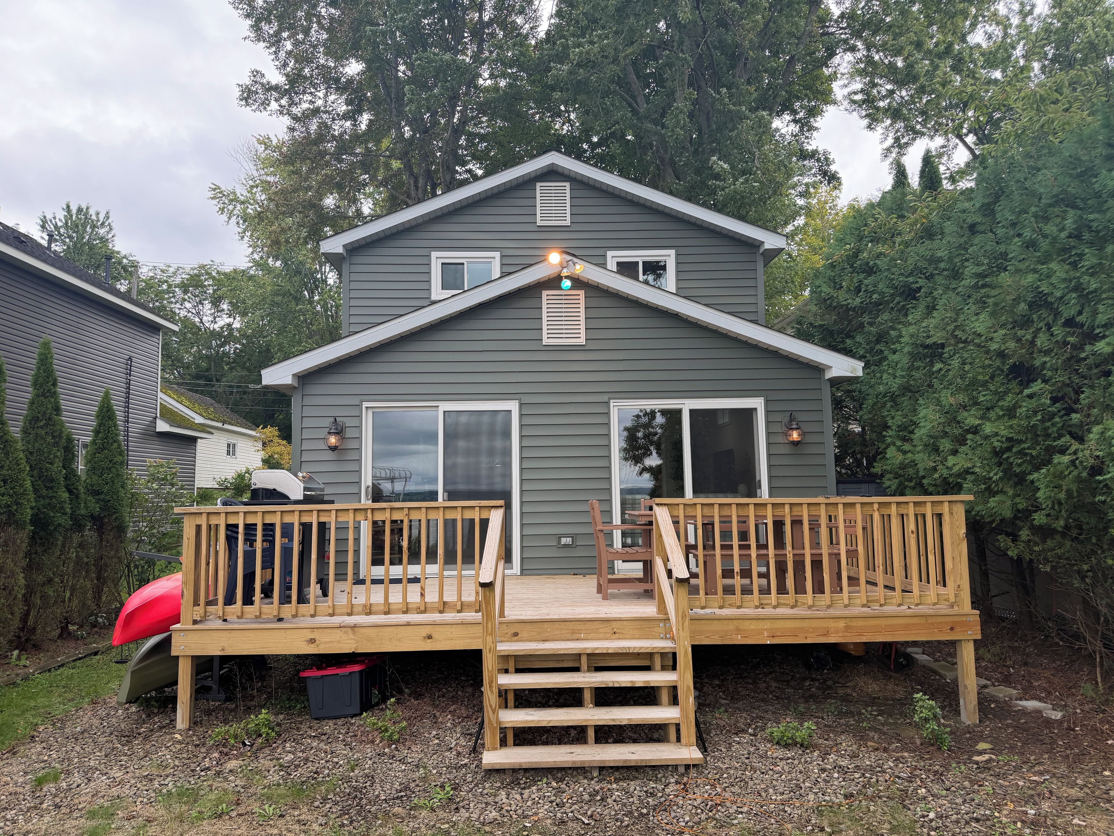 A two-story house with a wooden deck, a garage, and a red kayak.