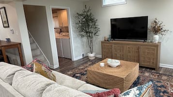 A living room with a sofa, a coffee table, a TV, and a plant.