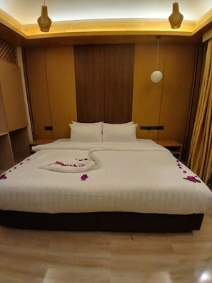 Ein Hotelzimmer mit einem großen Bett, einem Holzkopfteil und zwei Pendelleuchten.