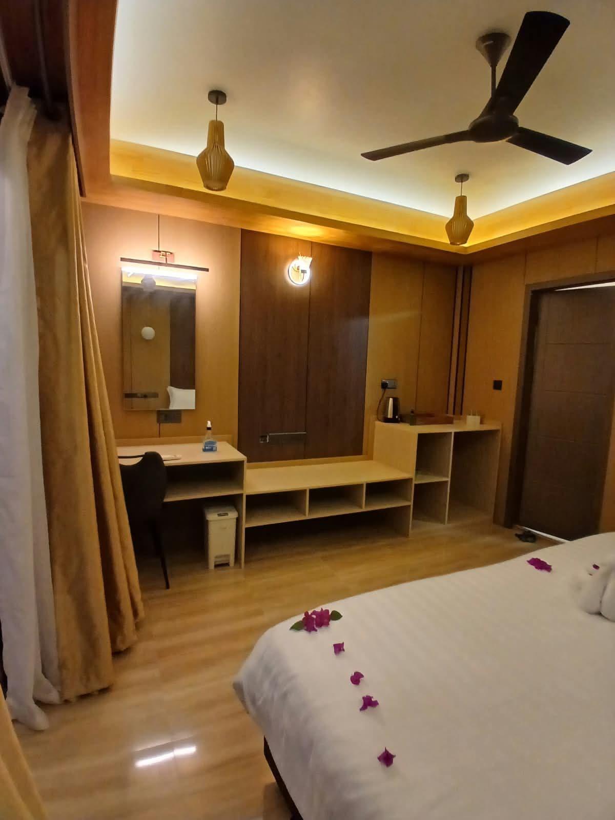 Une chambre d’hôtel équipée d’un lit, d’un bureau, d’une armoire et d’un ventilateur de plafond.