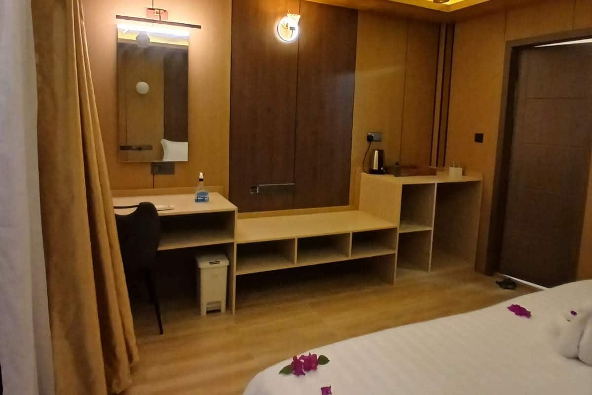Ein Hotelzimmer mit Bett, Schreibtisch, Kleiderschrank und Deckenventilator.