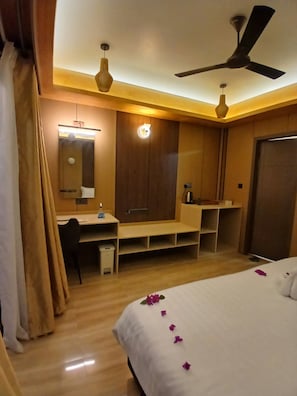 Ein Hotelzimmer mit Bett, Schreibtisch, Kleiderschrank und Deckenventilator.