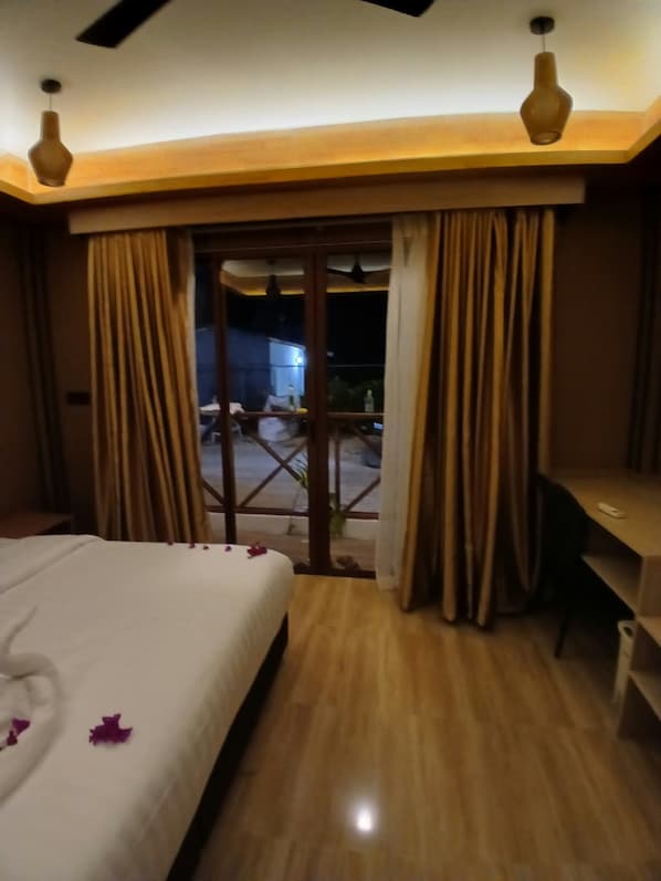 A hotel room with a bed, a desk, and a view of the outside. - Six Sail Maldives (Feridhoo)