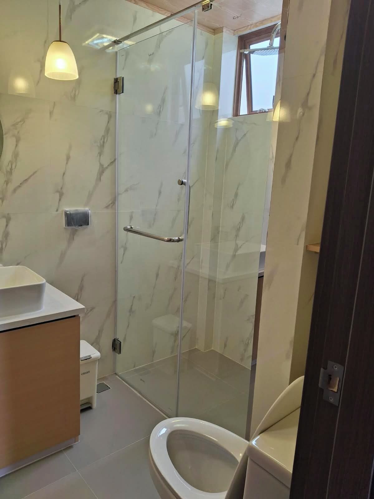 A modern bathroom with a glass shower enclosure, a toilet, and a vanity with a sink.