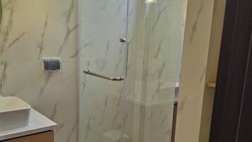 A modern bathroom with a glass shower enclosure, a toilet, and a vanity with a sink.