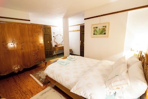 A bedroom with a wooden wardrobe, a bed with floral bedding, a small table, and a framed picture on the wall. - Villa Karusos , Pelion (Pelion)